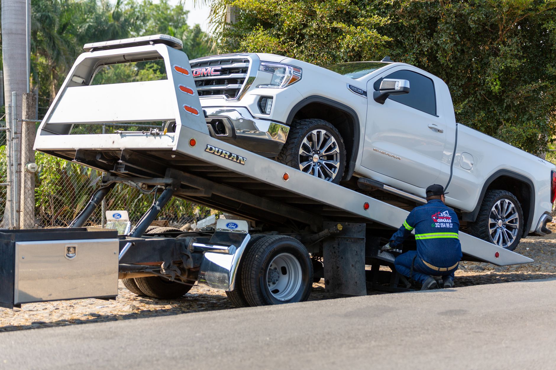 A Snappy Towing tow truck driver assisting a motorist with a flat tire on the side of a road in Lakewood, Colorado.